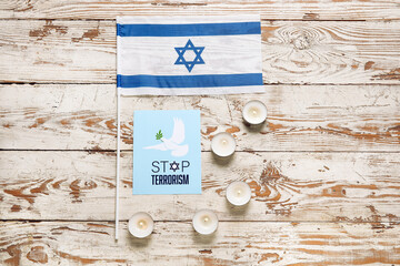 Flag of Israel, burning candles and card with text STOP TERRORISM on light wooden background