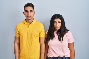 Fototapeta premium Young couple standing over isolated background relaxed with serious expression on face. simple and natural looking at the camera.