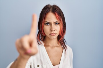 Obraz premium Young caucasian woman wearing casual white shirt over isolated background pointing with finger up and angry expression, showing no gesture