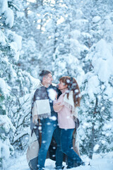 Fototapeta na wymiar A couple in love kissing while walking through a fabulously snow-covered winter forest