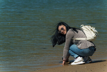 chinese woman squatting down at the waters edge