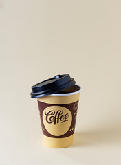 A cardboard cup with a black coffee lid with you on a light table. Beige background, space for text