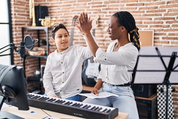 African american mother and son student and teacher with hands raised up at music studio