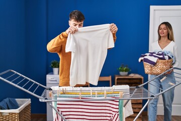 Young man and woman couple hanging clothes on clothesline at laundry room