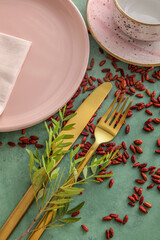 Stylish table setting with floral decor and scattered seeds on green background