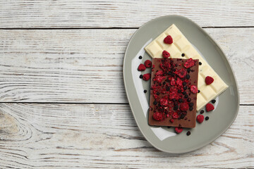 Plate and different chocolate bars with freeze dried fruits on white wooden table, top view. Space for text