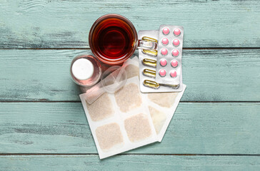 Mustard plasters with cup of tea, pills and cough syrup on color wooden background