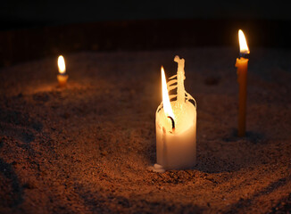 White Candles setting on the sand tray, lighting in the dark for religious ritual or spiritual,...