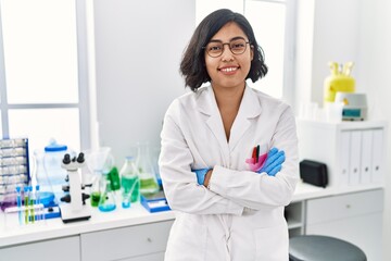 Young latin woman wearing scientist uniform standing with arms crossed gesture at laboratory