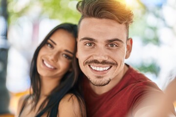 Fototapeta premium Man and woman couple making selfie by smartphone at park