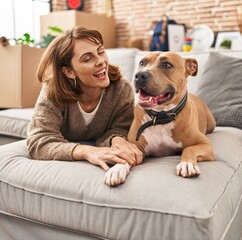 Young caucasian woman smiling confident lying on sofa with dog at new home