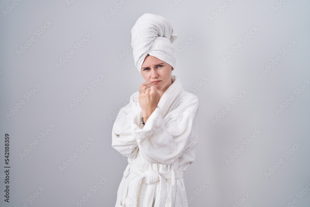 Wall mural Blonde caucasian woman wearing bathrobe ready to fight with fist defense gesture, angry and upset face, afraid of problem