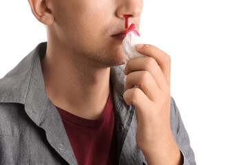 Young man with nosebleed and tissue on white background, closeup