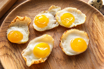 Wooden plate with tasty fried quail eggs, closeup