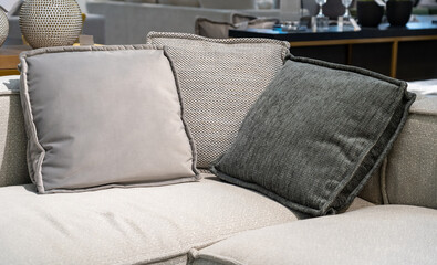 Close up light grey fabric sofa with warm cozy home interior background. Pillows on couch room decoration background