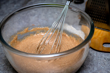 Glass bowl of whipped brown cream on kitchen table background, top view