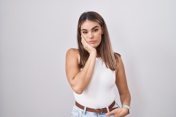 Hispanic young woman standing over white background thinking looking tired and bored with depression problems with crossed arms.