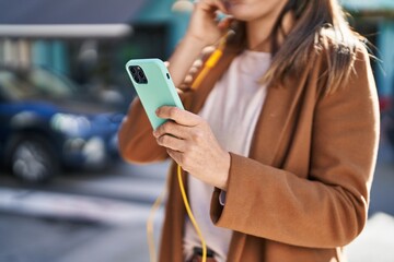 Young beautiful hispanic woman listening to music at street