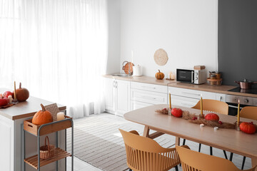 Interior of light kitchen with pumpkins, counters and dining table