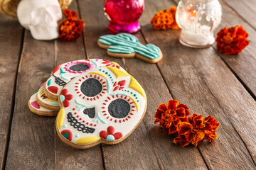 Skull shaped cookies and flowers on wooden background. El Dia de Muertos