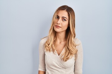 Young blonde woman standing over isolated background looking sleepy and tired, exhausted for fatigue and hangover, lazy eyes in the morning.