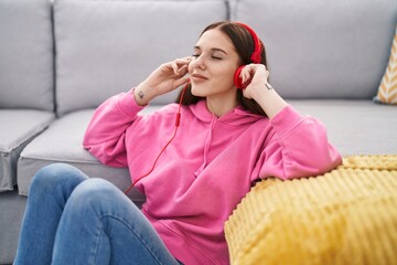 Young woman listening to music sitting on floor at home