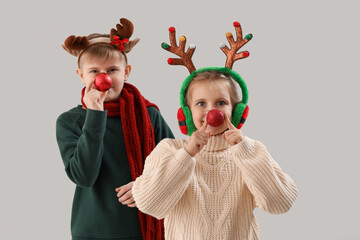 Happy little children in reindeer horns with Christmas balls on light background