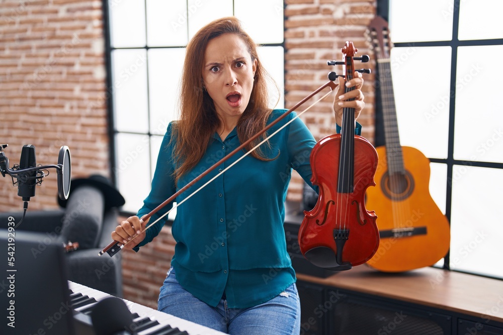 Canvas Prints brunette woman playing violin in shock face, looking skeptical and sarcastic, surprised with open mo