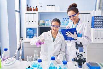 Fototapeta premium Woman and girl wearing scientist uniform working at laboratory