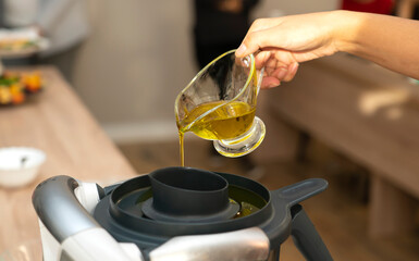 Master class in cooking. A cook pours oil into a food processor (blender) to make a salad dressing.