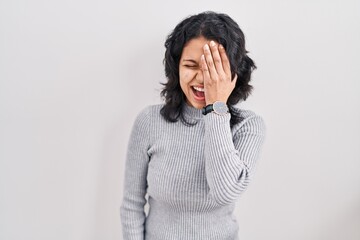 Hispanic woman with dark hair standing over isolated background yawning tired covering half face, eye and mouth with hand. face hurts in pain.