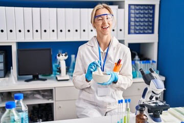 Young caucasian woman working at scientist laboratory winking looking at the camera with sexy...