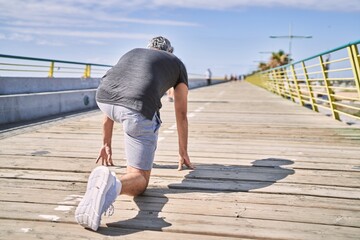 Middle age hispanic man wearing sportswear ready to run at street