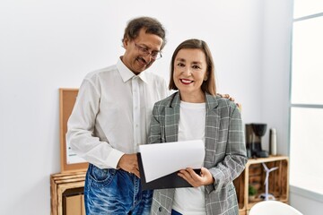 Middle age man and woman business workers smiling confident reading document at office