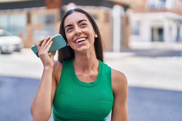 Young beautiful hispanic woman miling confident listening audio message by the smartphone at street