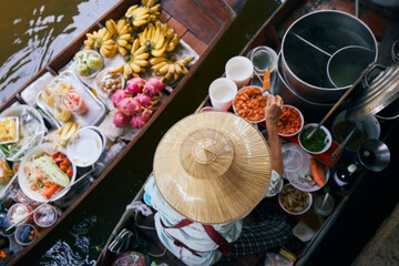 Fototapeta premium Selective focus on hat of vendor on boat on traditional floating market Damnoen Saduak near Bangkok, Thailand...
