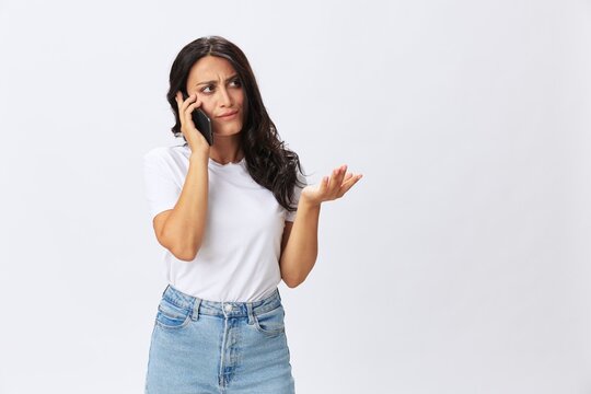 Woman blogger with a phone in her hands photo content, video call, selfie smile with teeth in a white t-shirt on a white background, copy space, emotions and gestures signals