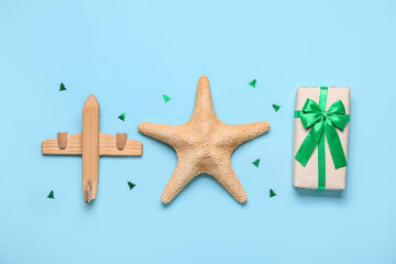 Wooden airplane with starfish and Christmas gift on blue background