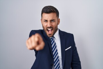 Handsome hispanic man wearing suit and tie pointing displeased and frustrated to the camera, angry and furious with you