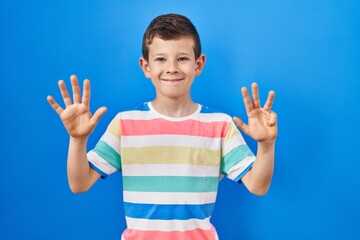 Young caucasian kid standing over blue background showing and pointing up with fingers number nine...