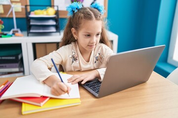 Adorable caucasian girl student using laptop writing on notebook at office