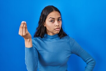 Fototapeta premium Young brazilian woman standing over blue isolated background doing italian gesture with hand and fingers confident expression