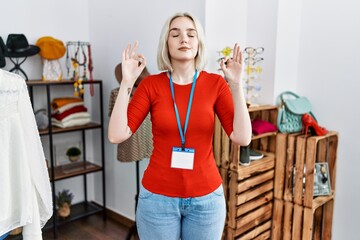 Young caucasian woman working as manager at retail boutique relax and smiling with eyes closed doing meditation gesture with fingers. yoga concept.