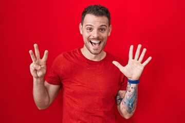 Young hispanic man standing over red background showing and pointing up with fingers number eight while smiling confident and happy.