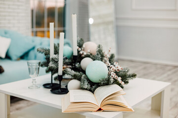 An open book on the table, candles and a Christmas wreath in the living room