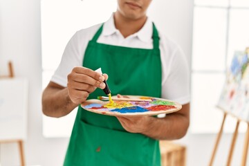 Young hispanic man mixing color at art studio