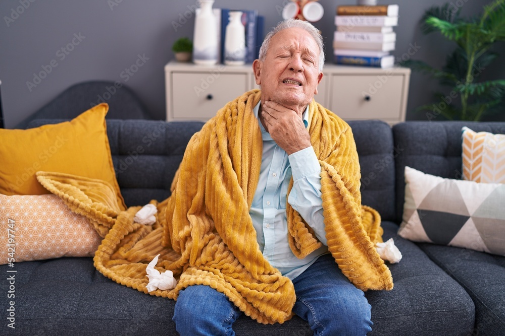 Poster middle age grey-haired man suffering for throat pain sitting on sofa at home