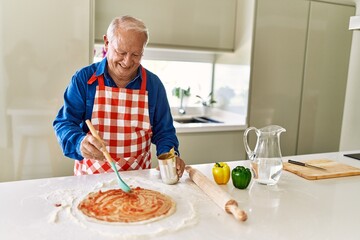 Senior man smiling confident cooking pizza at kitchen