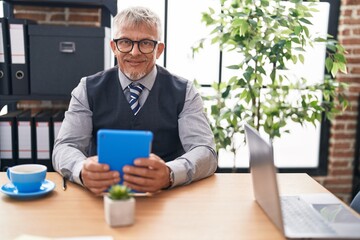 Middle age grey-haired man business worker using touchpad at office