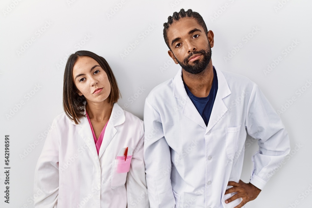 Poster Young hispanic doctors standing over white background looking sleepy and tired, exhausted for fatigue and hangover, lazy eyes in the morning.